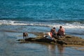 Black Dog and Two Young Boys seated on Reef near Sea Royalty Free Stock Photo