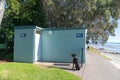 Black dog waits tied to post outside public toilet block Royalty Free Stock Photo