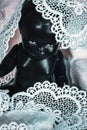 Black doll covered in white lace