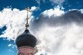 Black dome of the Church with a golden cross on the sky background with white clouds. tower of the old red brick in the light of t Royalty Free Stock Photo