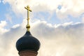 Black dome of the Church with a golden cross on the sky background with white clouds. tower of the old red brick in the light of t Royalty Free Stock Photo