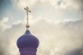 Black dome of the Church with a golden cross on the sky background with white clouds. tower of the old red brick in the light of t Royalty Free Stock Photo