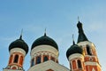 Black domes with crosses on top of painted in red and white orthodox church, The Holy Treasury Saints Temple, bright blue sky Royalty Free Stock Photo