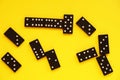 Black domino bones on yellow background close up