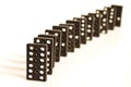 Black domino pieces standing in line in front of white background Royalty Free Stock Photo