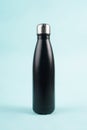 A black drinking bottle is placed on a light blue background, creating a modern and refreshing look Royalty Free Stock Photo