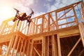 Black drone quadcopter with camera flying over residential construction home framing against a blue sky. Royalty Free Stock Photo