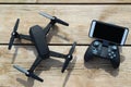 Black Drone quadcopter with a remote control and phone on wood table