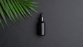 Black dropper bottle mockup and palm leaf on black background. Herbal cosmetic, natural organic beauty product, essential oil