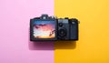 DSLR camera on pink and yellow background with sunset on screen Royalty Free Stock Photo