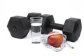 Black dumbbells, cup, tape measure and apple on a white background. Royalty Free Stock Photo