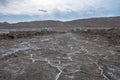 Black earth covered with salt against a blue sky with mountains in the background Royalty Free Stock Photo