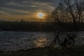 Black electric bicycle with sunset near weir on Malse river