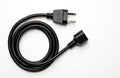 Black electric extension cord with plug and socket on white background. Coiled wire connects power for appliances. It is simple Royalty Free Stock Photo