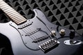 Black electric guitar lying on acoustic foam panel