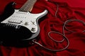 Black electric guitar, red background, nobody