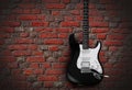 Black electric guitar on red brick wall background Royalty Free Stock Photo