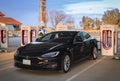 Black electric luxury Tesla Model S performance car at a supercharger Royalty Free Stock Photo