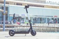 Black electric scooter parking on a deck at Tel Aviv Port commercial district on a summer sunny day