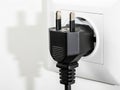 Black electrical plug inserted in wall socket Royalty Free Stock Photo