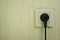 Black electrical plug in a white plastic socket on the wall Royalty Free Stock Photo