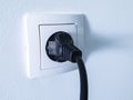 Black electrical power plug connected inside a white plastic power socket Royalty Free Stock Photo