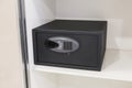 Black electronic safe with a digital keypad installed on a white shelf, concept of security, protection, valuables and modern Royalty Free Stock Photo