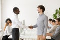 Black employer shaking hand of shy male Caucasian job applicant