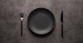 black empty plate and cutlery, fork and knife, on a dark textured background. Mockup concept for the design of a Royalty Free Stock Photo