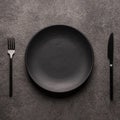 black empty plate and cutlery, fork and knife, on a dark textured background. Mockup concept for the design of a Royalty Free Stock Photo