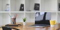 Empty screen laptop is putting on a wooden working desk surrounded by office equipment. Royalty Free Stock Photo