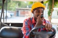 Black engineer is talking on the walkie-talkie while sitting in a forklift