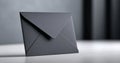 A black envelope is sitting on a white surface with the flap open and slightly folded over itself, in front of a grey background Royalty Free Stock Photo