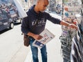 Black ethnicity man buying newspaper reporting handover ceremony