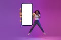 Black Excited Woman Jumping With Blank Smartphone In Hand Under Neon Light Royalty Free Stock Photo