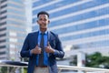 black executive man in blue suit and tie standing, cheerful, and looking at camera outside building in city.