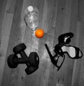 Exercise barbells , water bottle, orange and high hills on the wooden floor