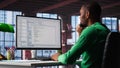 Black IT expert looking at user interface on computer at home office Royalty Free Stock Photo