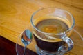 Black expresso coffee in small glass cup on wooden table with te Royalty Free Stock Photo