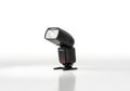 A black external camera flash unit angled forward on a clean white background isolated on white background Royalty Free Stock Photo