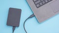 Black external hard disk connecting to a laptop on a blue background Royalty Free Stock Photo