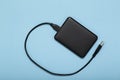 Black external hard disk with USB cable on blue background. Royalty Free Stock Photo