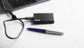 Black external portable SSD on white background next to laptop and blue pen. Portable Solid State Drive. The concept of modern Royalty Free Stock Photo