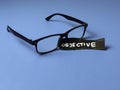 Black Eyeglasses with Objective Sign on Blue Background Representing Clear Vision Unbiased Judgment and Professional Neutrality in Royalty Free Stock Photo