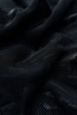 Black fabric with grid pattern shows smooth texture and natural weave. High-quality material highlighted by blurred background.