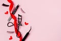 Black false eyelashes and tweezers on pink background with red hearts and ribbon , copy space Royalty Free Stock Photo