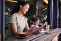 Black family, children and mother remote working at a cafe together with her daughter coloring in a book. Tablet Royalty Free Stock Photo