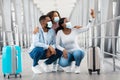 Black family in face masks taking selfie in airport