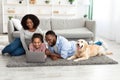 Black family at home using laptop relaxing with dog Royalty Free Stock Photo