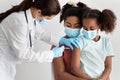 Black family making vaccination at clinic, wearing face masks